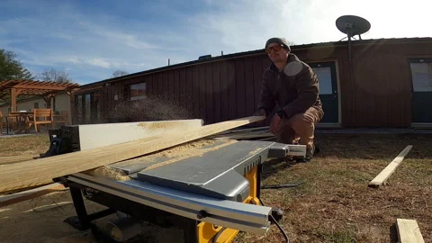 CARPENTER WORKING USING TABLESAW ON COLD WINTER DAY Stock Footage 168656367