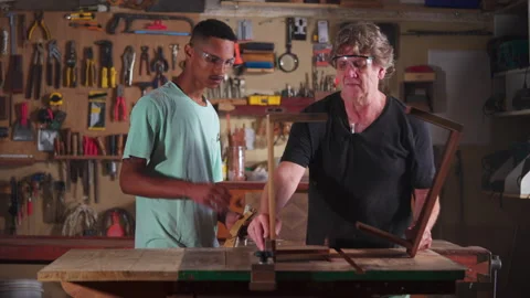 Carpenter working at workshop with the help of apprentice, small business w.. Stock Footage 255865946