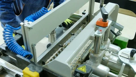 A carpenter works behind a drilling machine, adding furniture parts to a Stock Footage 104821140