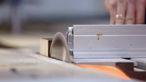 Carpenter works behind machine tool, cuts thin piece of wood with circular saw Stock Footage 128391505