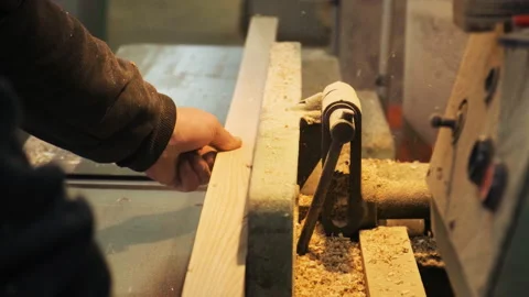 Carpenter works on the jointer-planer or surface planer with wooden plank.  Wood Stock Footage 235835037