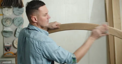 A carpenter works in a workshop. A carpenter is grinding a wooden part with Stock Footage 170321112