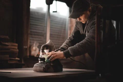A carpenter works in a workshop. Joiner's grinders, furniture manufacturing.  Stock Photos