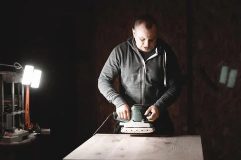 A carpenter works in a workshop. Joiner's grinders, furniture manufacturing.  Stock Photos