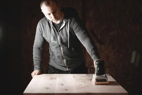 A carpenter works in a workshop. Joiner's grinders, furniture manufacturing.  Stock Photos