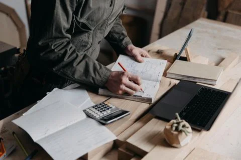 Carpenter writes on a notebook 스톡 사진