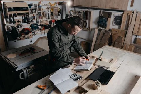Carpenter writes on a notebook Stock Photos