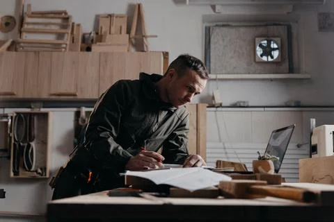 Carpenter writes on a notebook 스톡 사진