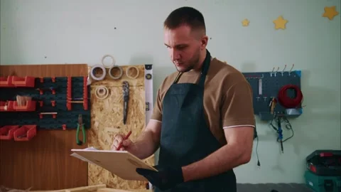 Carpenter writing notes on clipboard in workshop Stock-Footage 308931773