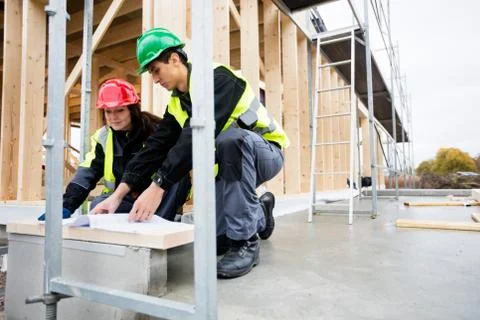 Carpenters Analyzing Document At Construction Site 写真素材