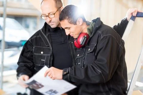 Carpenters Looking At Plan While Standing At Site Фото