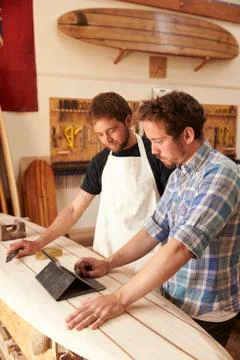 Carpenters In Surfboard Workshop Using Digital Tablet Stock Photos