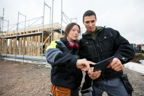 Carpenters Using Digital Tablet At Construction Site Stock Photos