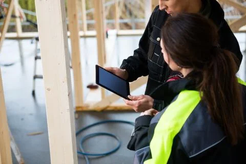 Carpenters Using Digital Tablet In Incomplete Architecture Stock Photos