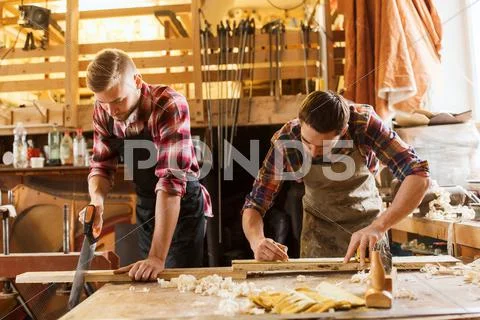 Carpenters working with saw and wood at workshop Stock Photos
