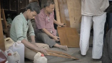 Carpenters working while sitting on the ground in a roadside workshop Stock Footage 85873575