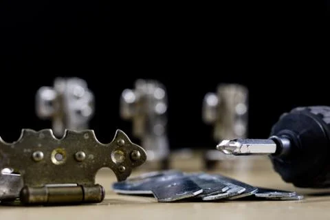Carpentry tools and accessories on a workshop table. Hinges and screws togeth Stock Photos