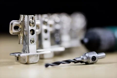 Carpentry tools and accessories on a workshop table. Hinges and screws togeth Stock Photos
