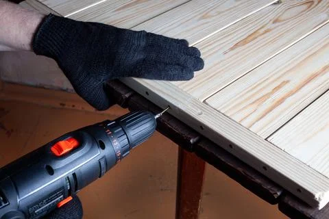 Carpentry work. The self-tapping screw is screwed into a wooden beam. Furniture Stock Photos