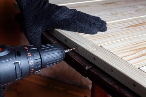 Carpentry work. The self-tapping screw is screwed into a wooden beam. Furni.. Stock Photos