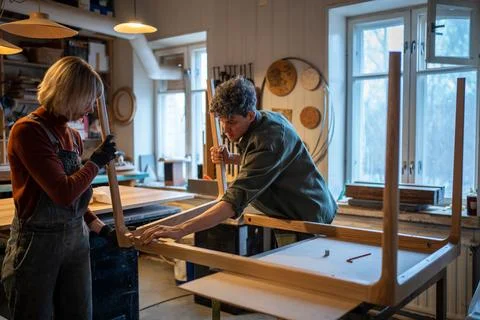 Carpentry workshop, craftsmen working together. Woman and man assembling table Foto stock