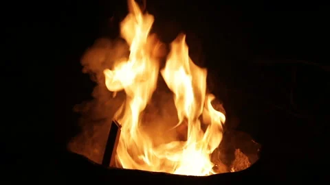 The carpet burns in a round garbage can at night. close-up. Stockbeeldmateriaal 85902197