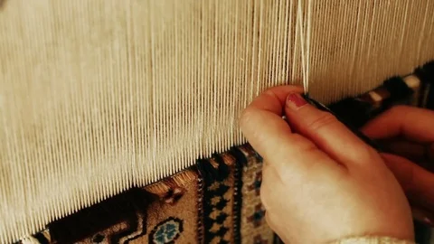 Carpet weaving. Turkish woman weaving a carpet with peace of genuine camel wool Stock Footage