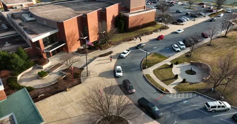Carpool lineup outside school building in USA. American flag on pole Stock Footage 171650252