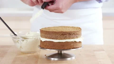 A carrot cake being spread with cream cheese creme Stock Footage 24671711