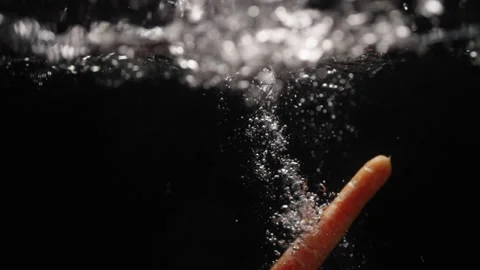 Carrot falling into water in slowmotion Stock Footage 254585557