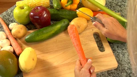 Carrots and assorted vegetables being skinned and peeled on cutting board Video stock 123731910