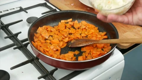 Carrots and onions are fried in a pan at home, close-up, wooden spoon Stock Footage 133715053