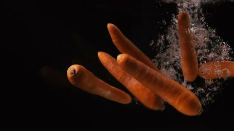 Carrots falling into water with bubbles on black background. Vegetables falling Stock Footage 134667691