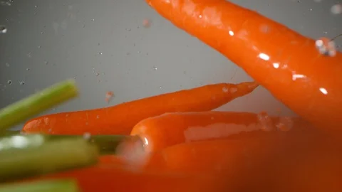 Carrots falling on water surface. Slow Motion. Stock Footage 128770927