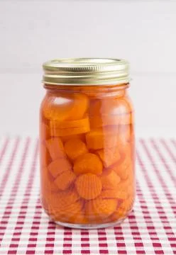Carrots on a Red Gingham Table Cloth in a Home Canning Jar Stock Photos