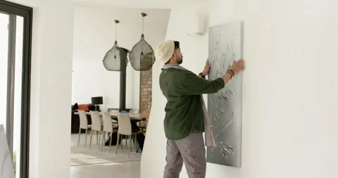 Carrying abstract canvas from inside living room, homeowner is decorating wall, Stock Footage 342233266