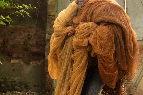 Carrying a large bundle of tan-colored fishing nets. Stock Photos