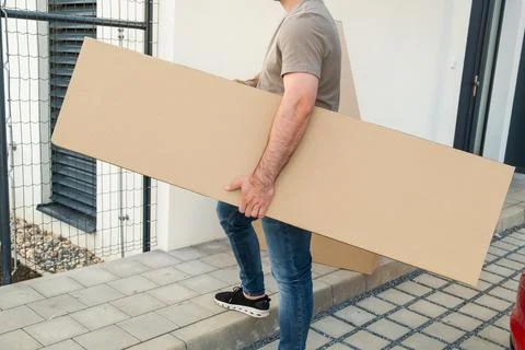 Carrying large cardboard panel during home renovation project outdoor Stock Photos