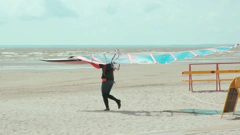 Carrying windsurfing equipment at a beach Stock Footage