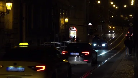 Cars and a tram drive on a road in a street at night Stock Footage