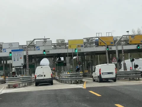 Cars and vans queue at a highway toll plaza, with electronic signs displayi.. Stock Footage 328389880