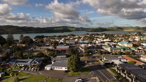 Cars circle busy roundabout intersection near town shops and helicopter pad at Stock-Footage 341683376