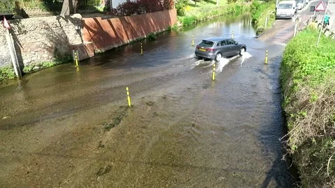 Cars cross the ford on the River Sid at Sidmouth, Devon, England, UK Stock Footage 153613576