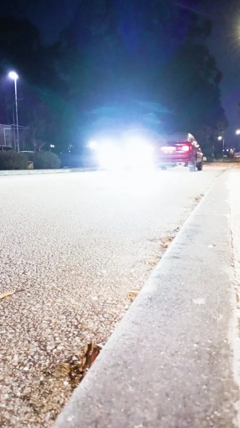 Cars driving back and forth on a quiet small town street at night, low angle Stock Footage 324810981