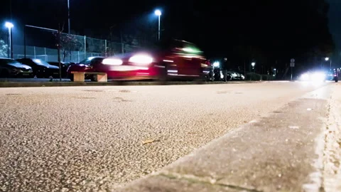 Cars driving back and forth on a quiet small town street at night, low angle Stock Footage 325241353