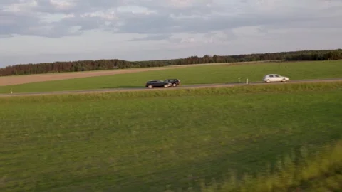 Cars driving on the road between the fields	 in sunset Stockbeeldmateriaal 243512052