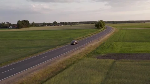 Cars driving on the road between the fields	 in sunset Stockbeeldmateriaal 243512061