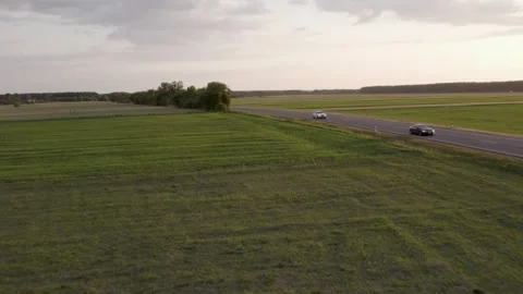 Cars driving on the road between the fields	 in sunset Video stock 243512062