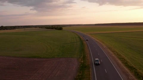 Cars driving on the road between the fields	 in sunset Stockbeeldmateriaal 243512068