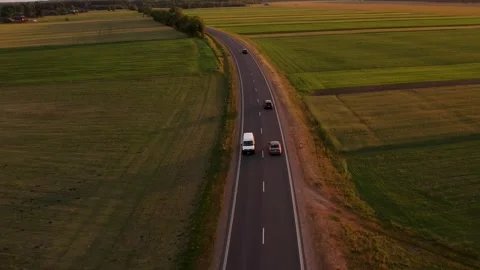Cars driving on the road between the fields	 in sunset Stockbeeldmateriaal 243512070